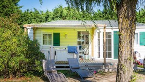 A yellow house with a porch, two lounge chairs, and a tree in the foreground. - CampingSpa - Privilège 2 – 4p  (1) (La Couarde-sur-Mer)
