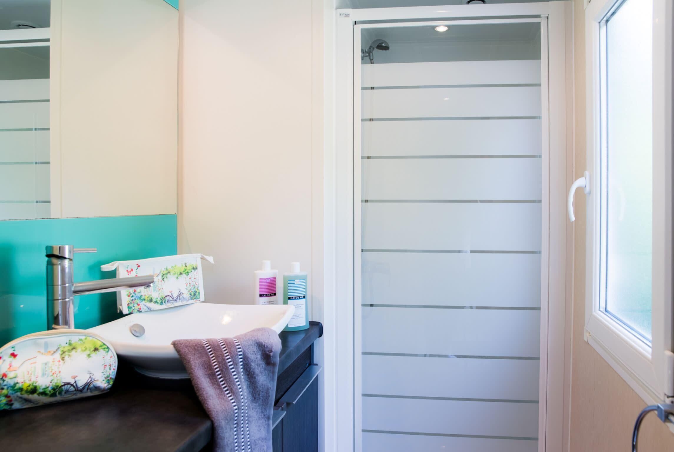 A bathroom with a white sink, a mirror, and a shower with horizontal lines.
