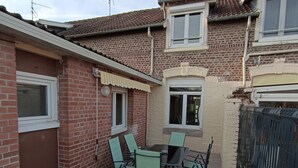 Een terras met een tafel en stoelen, een bakstenen muur en een zwart metalen hek.