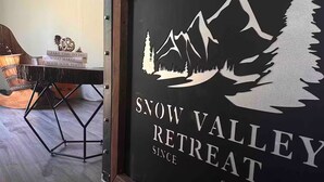 Une plaque encadrée, ornée d’un motif représentant une montagne et un arbre, sur laquelle on peut lire : « Snow Valley Retreat 2023 ».