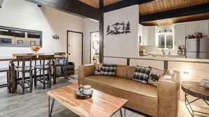 Un salon moderne avec une table basse en bois, un canapé en cuir et un coin repas comprenant une table et des chaises en bois.