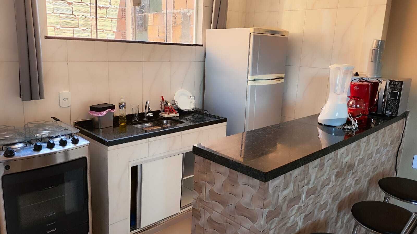 A compact kitchen with a gas stove, a built-in oven, a refrigerator, and a coffee maker.