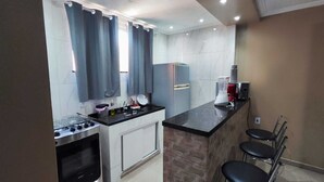 A compact kitchen with a gas stove, a sink, a refrigerator, and a countertop. - Complete Studio 3 (Rio das Ostras)