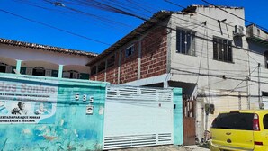 A residential building with a blue gate and a yellow car parked in front. - Complete Studio 3 (Rio das Ostras)
