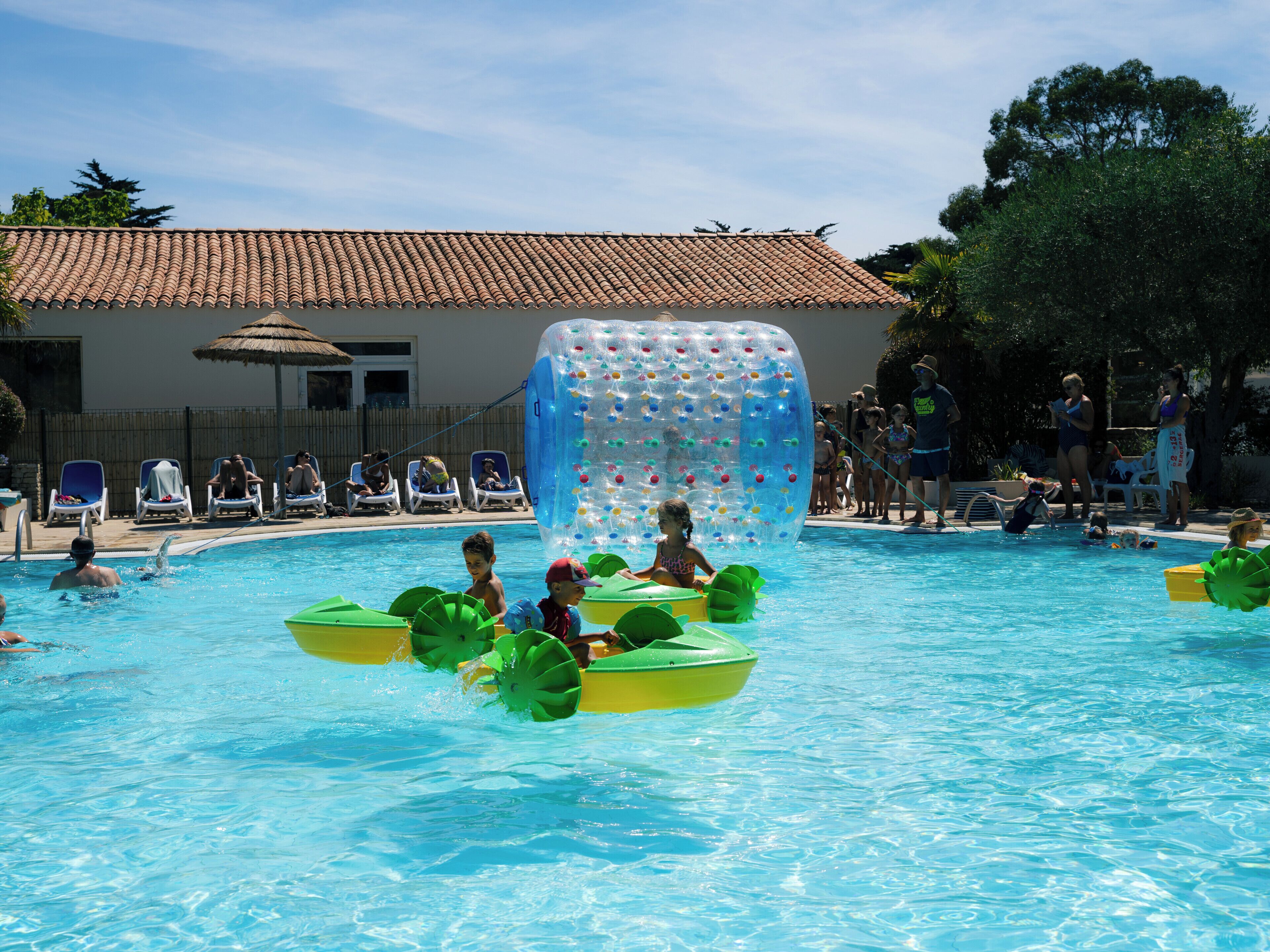 A swimming pool with inflatable boats and a water slide.