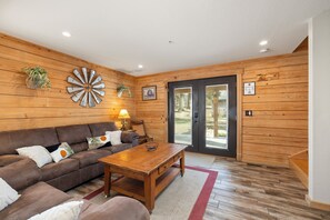 A wooden interior with a sofa, coffee table, and decorative wall pieces. - Gorgeous cabin with river access, fire pit, fast wifi and a great location! (Hollister)