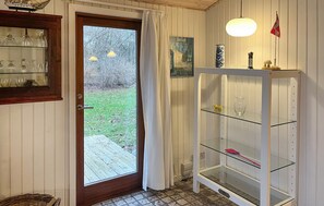 A room with a wooden door, a glass cabinet with shelves, and a small table with a lamp. - Pet friendly home in 24rup with WiFi (24rup)
