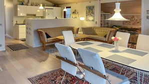 Una cocina moderna con armarios blancos, un banco de madera y una zona de comedor con mesa y sillas blancas.