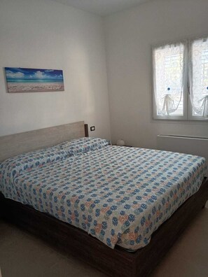 A bedroom with a bed, a painting on the wall, and a window with curtains. - Villa Piro: detached villa with garden, veranda and BBQ, Litorale di Manduria (Urmo)
