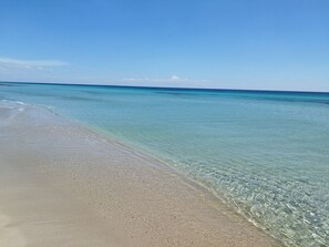 Ein Strand mit klarem türkisblauem Wasser und einem sandigen Ufer.