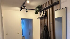 A modern interior with a wooden floor, a bench, a mirror, and a plant. - Old Town Residence Warendorf (Warendorf)