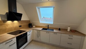 A modern kitchen with a built-in oven, a coffee maker, and a window with a view of buildings. - Old Town Residence Warendorf (Warendorf)