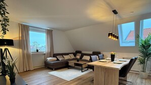 A modern loft apartment with a living area, dining space, and a large window providing natural light. - Old Town Residence Warendorf (Warendorf)