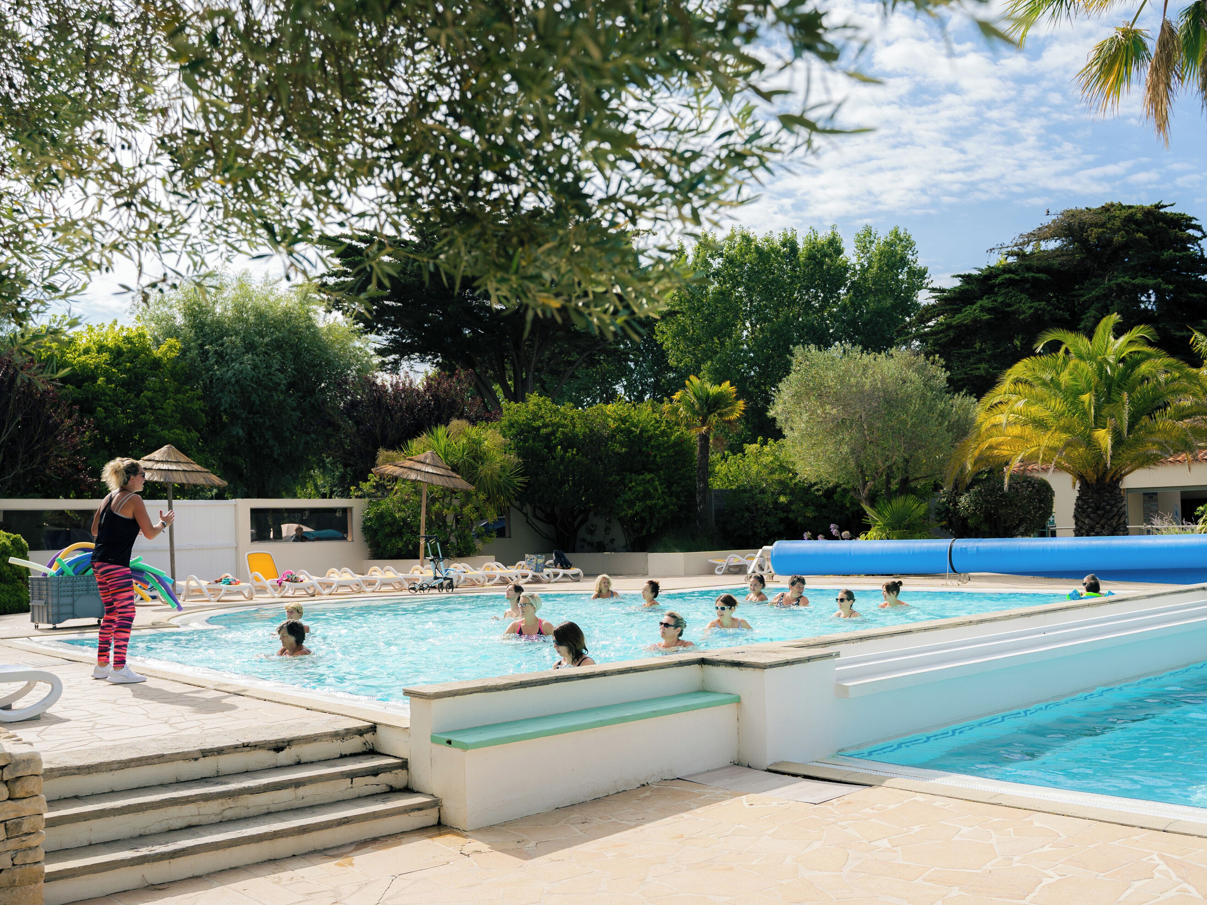 Ett poolområde med flera pooler, solstolar och en person som står vid poolen.