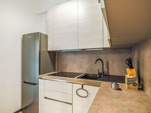 A compact kitchen with a built-in refrigerator, a sink, and a countertop. - La terrazza di Alessia e Luca by Interhome (Rapallo)