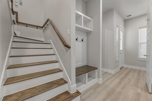 Eine Treppe mit Holzbodenstufen und weißen Wänden, die zu einer Zwischenebene mit Einbauschränken führt.