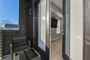 Ein modernes Zimmer mit einer Schiebeglastür, einem Korbstuhl und Blick ins Freie.