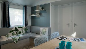 Quarto moderno com sofá, mesa de jantar e janela com cortinas.