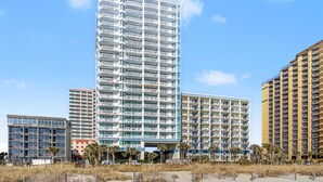 Un hôtel à plusieurs étages doté de balcons, d’un atrium central et offrant une vue sur la plage.