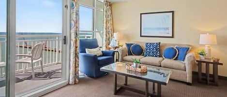 A room with a balcony, a sofa, a chair, a coffee table, and two lamps.