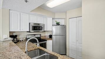 A kitchen with white cabinets, stainless steel appliances, granite countertops, and a built-in oven.