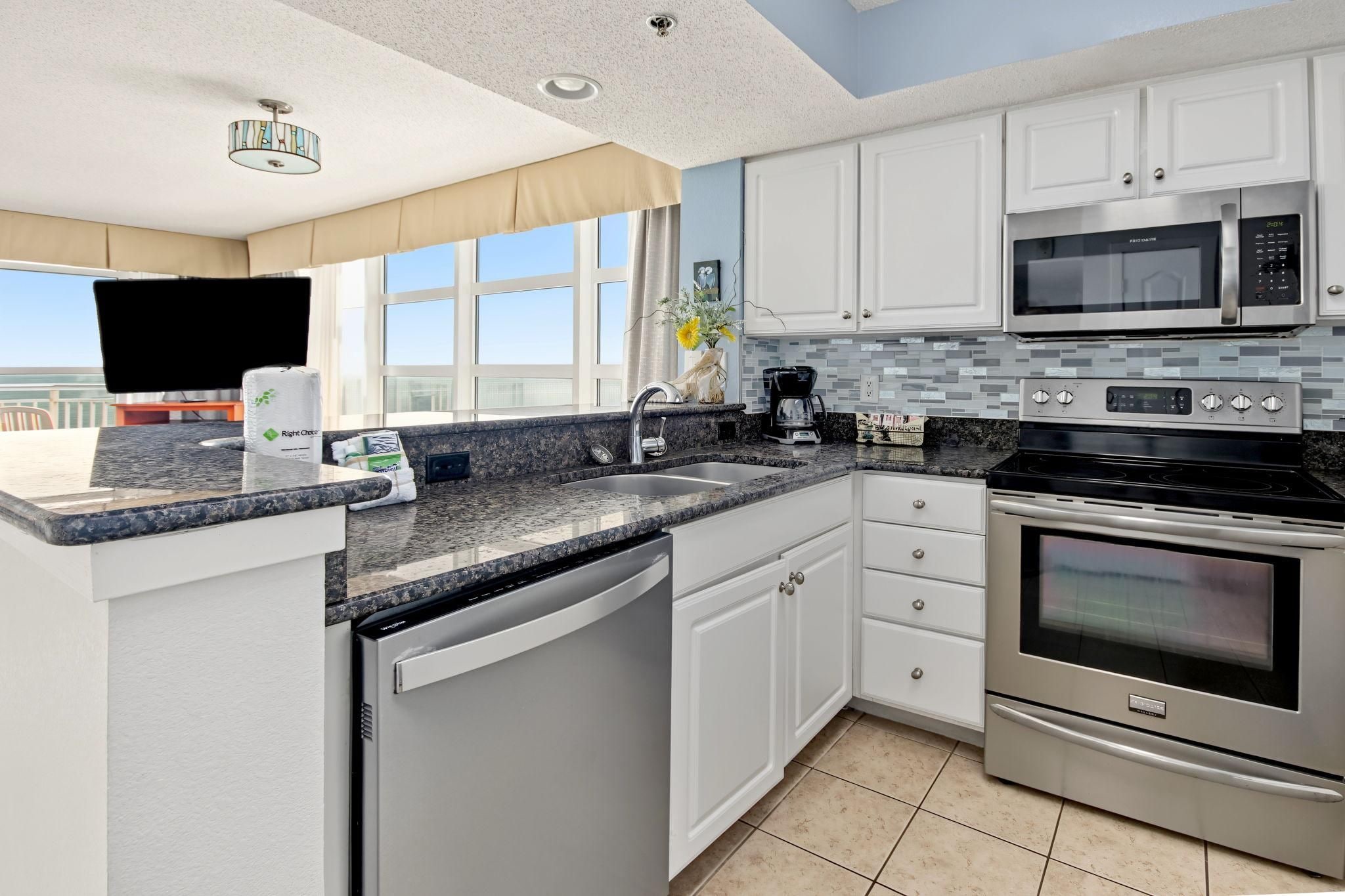 A modern kitchen with a dishwasher, double oven, and a microwave.