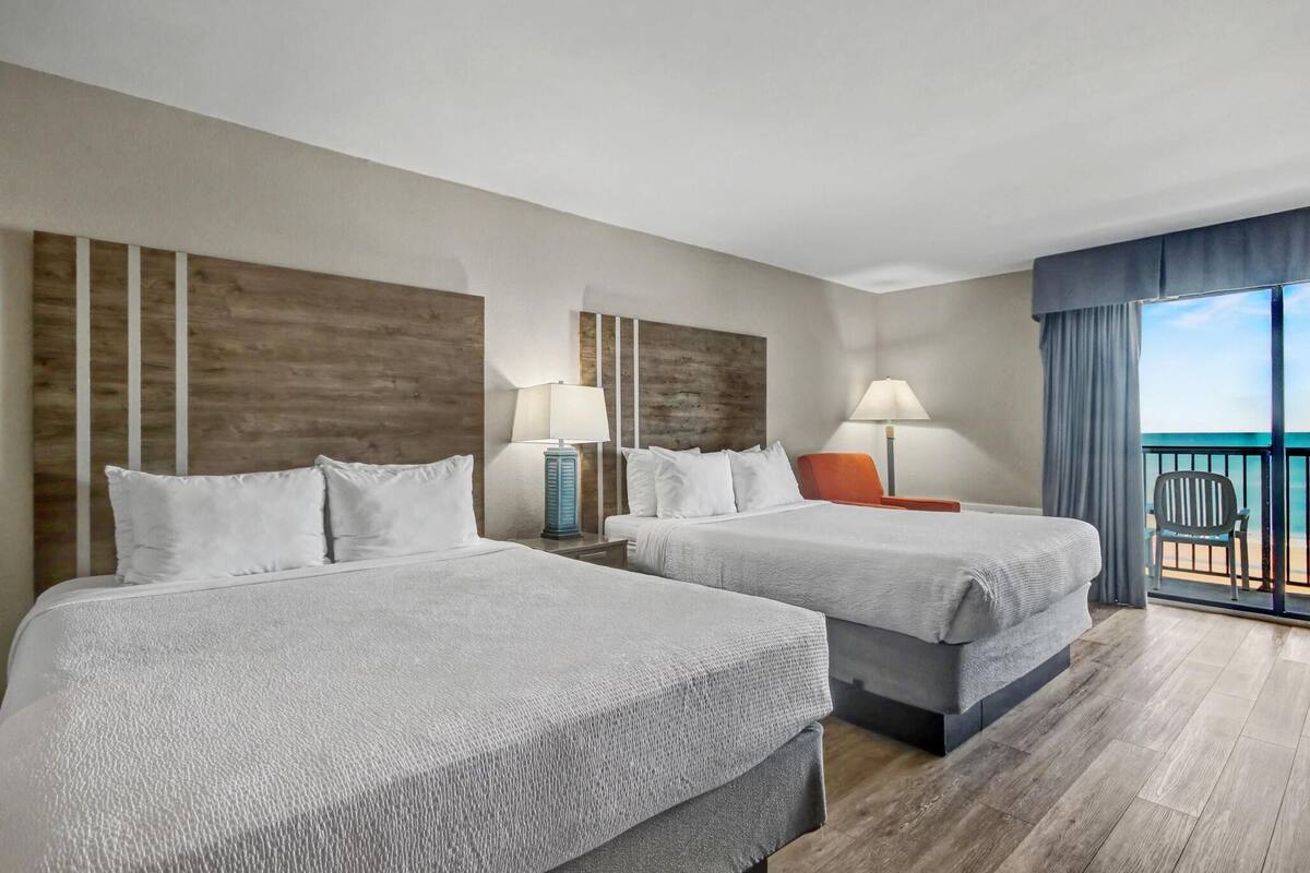 Habitación de hotel con dos camas, un balcón y una vista panorámica, junto con un ventanal grande.