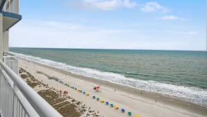 A beach view from a balcony with a railing, a sandy beach, and the ocean. - Carolinian Beach Resort (Myrtle Beach)