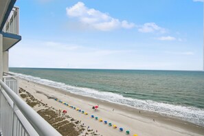 A beach view from a balcony with a railing, a sandy beach, and the ocean. - Carolinian Beach Resort (Myrtle Beach)