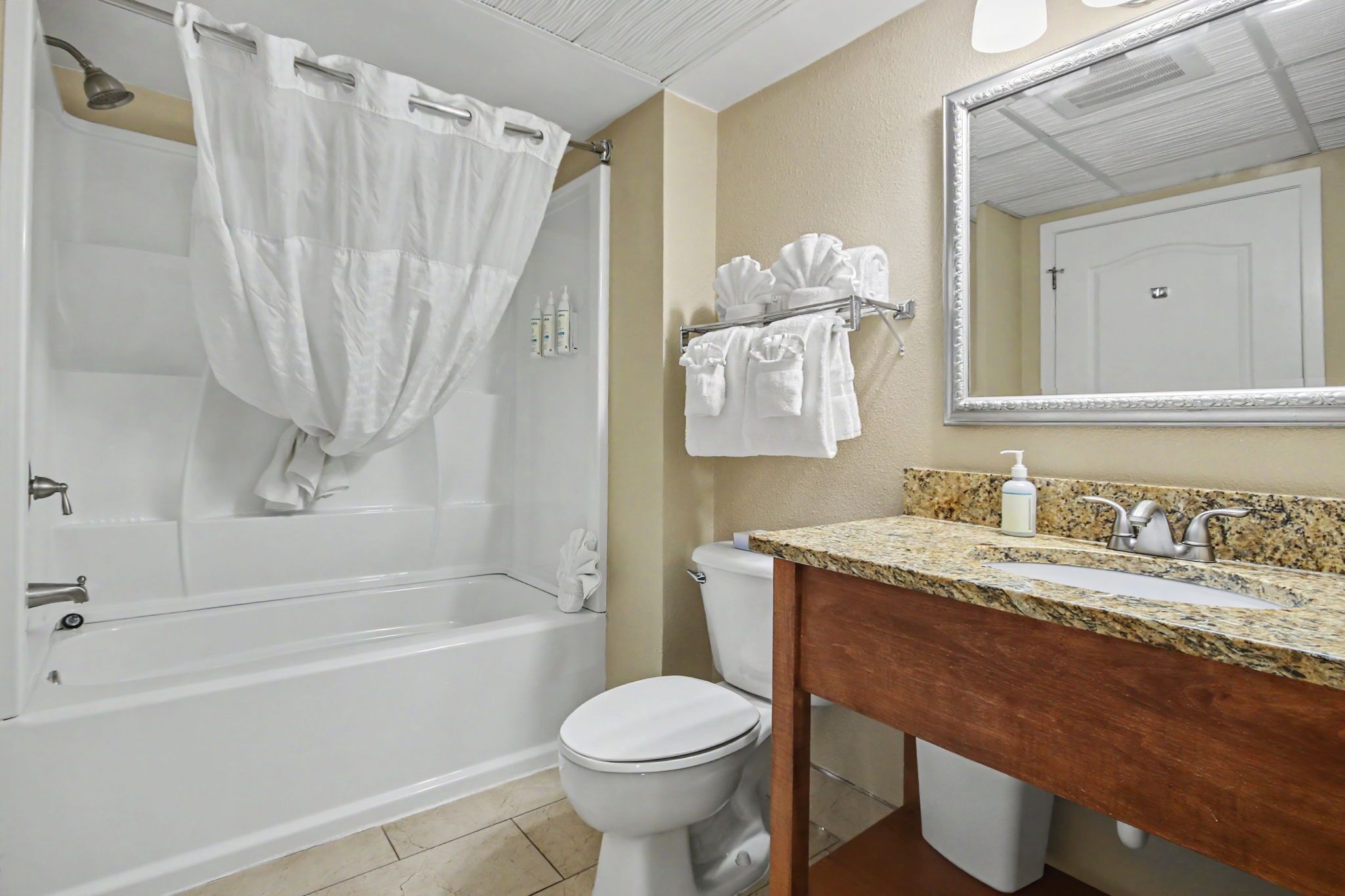 A bathroom with a bathtub, toilet, sink, and a mirror.
