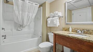 A bathroom with a bathtub, toilet, sink, and a mirror.