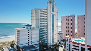 A high-rise hotel with multiple floors, a swimming pool, and a beach view. - Carolinian Beach Resort (Myrtle Beach)