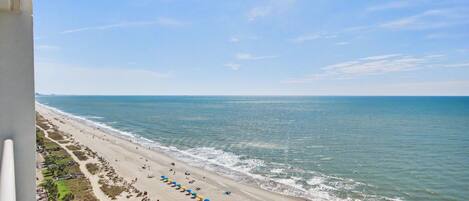 A beach with umbrellas, a clear sky, and the ocean.