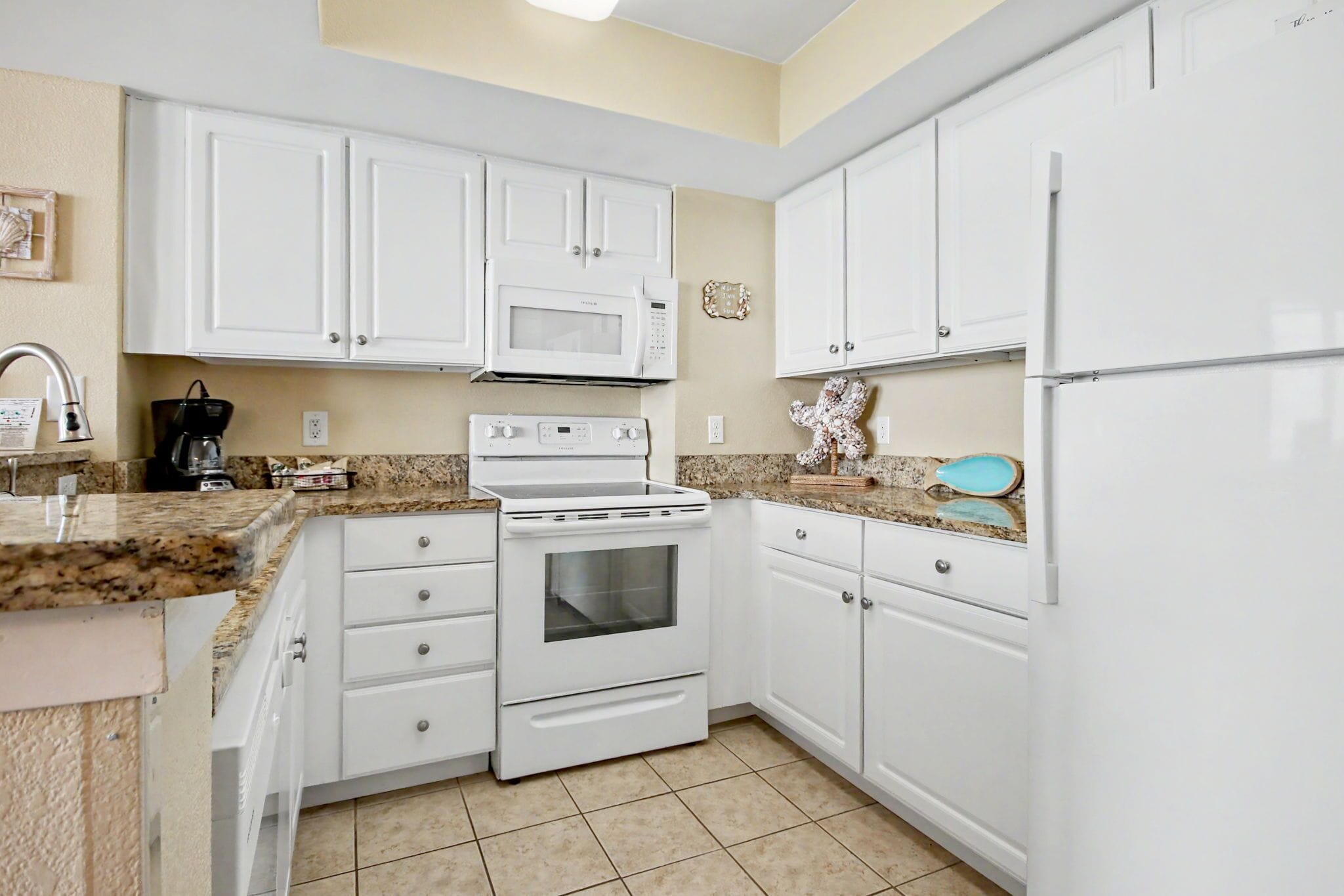 A kitchen with white cabinets, a microwave, an oven, and a refrigerator.