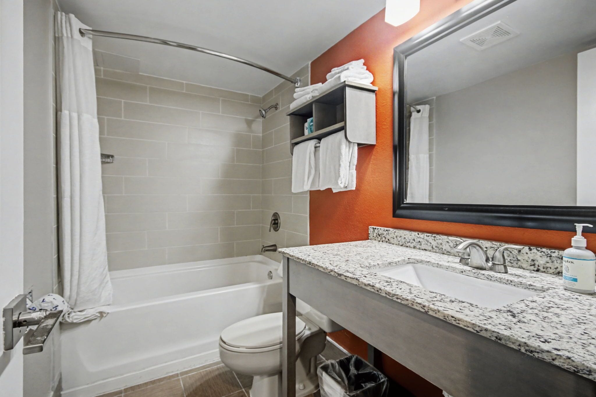 A bathroom with a bathtub, toilet, sink, and a mirror.