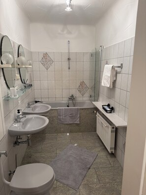 Une salle de bain avec deux lavabos, une baignoire, des toilettes et une douche.
