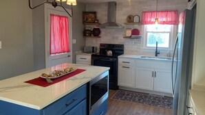 Una cocina con armarios blancos, una isla azul, una estufa y un microondas.