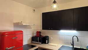 Een kleine keuken met een rode koelkast, een magnetron, een koffiezetapparaat en zwarte kastjes.