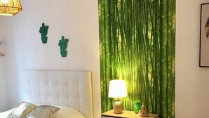 Een slaapkamer met een bed, een nachtkastje, een lamp en een muur met een bamboibos muurschildering.