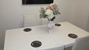 Una mesa de comedor con cuatro sillas, un jarrón con flores y un cuadro en la pared.