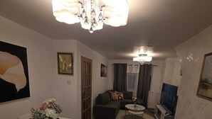Un espacio habitable compacto con comedor, sofá, televisor y candelabro.