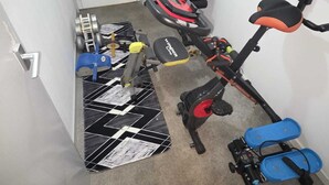 Un gimnasio en casa con equipo de ejercicio, incluyendo una bicicleta estática, una banca, mancuernas y una pelota de ejercicios grande.
