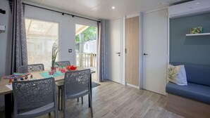 Et moderne værelse med spisebord, stole, sofa og en skydedør til et udendørs område.
