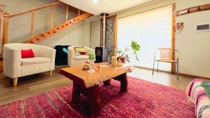 Een gezellige woonkamer met een houten trap, een open haard en een groot raam.