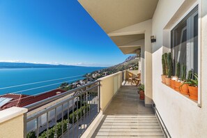Un balcon avec vue sur la mer, des plantes en pot et une chaise.