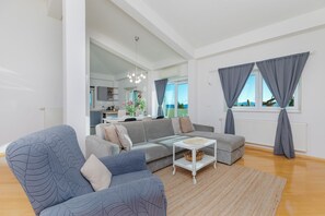A modern living room with a grey sectional sofa, a white coffee table, and a large window with grey curtains. - Luxury Penthouse, Sea View Terrace 100m2, Jacuzzi, BBQ, 8 Guests, Private floor (Mimice)