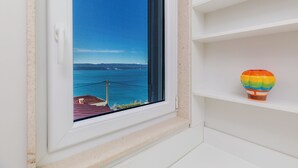 Ein Fenster mit Meerblick und einem Heißluftballon auf einem Regal.