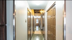 A hallway with wooden doors, a light-colored floor, and a ceiling light fixture. - Sleek Industrial Loft in Short North Near OSU with King Beds & Fast WiFi (Columbus)