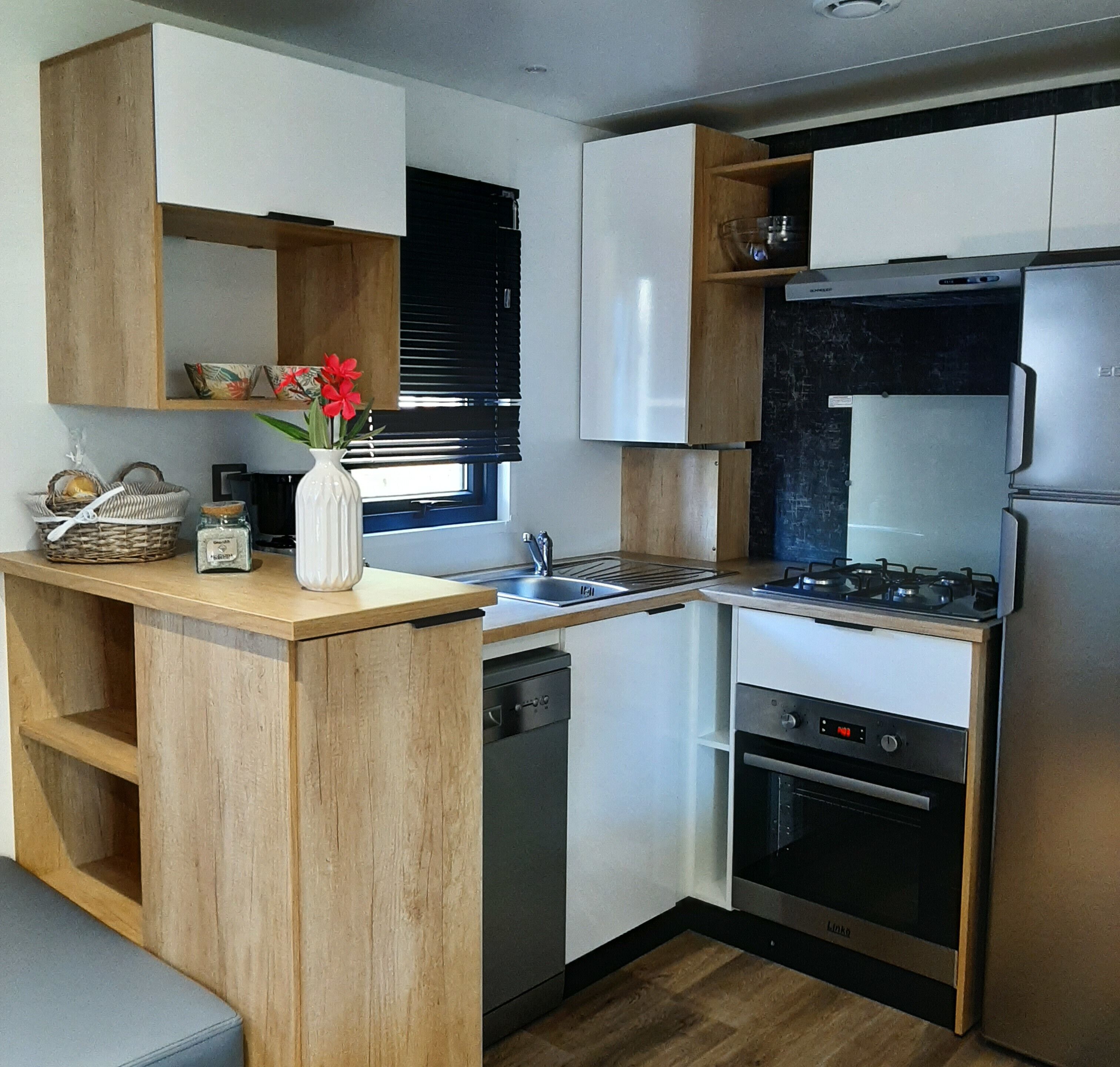 A compact kitchen with wooden cabinets, a built-in oven, a refrigerator, and a small sink.