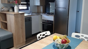 Une cuisine compacte dotée d’appareils électroménagers modernes, un coin repas avec une table et un petit espace salon.